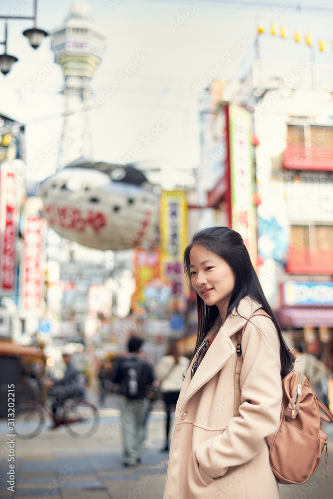 Asian young woman is traveling at Shinsekai, Osaka, Japan.