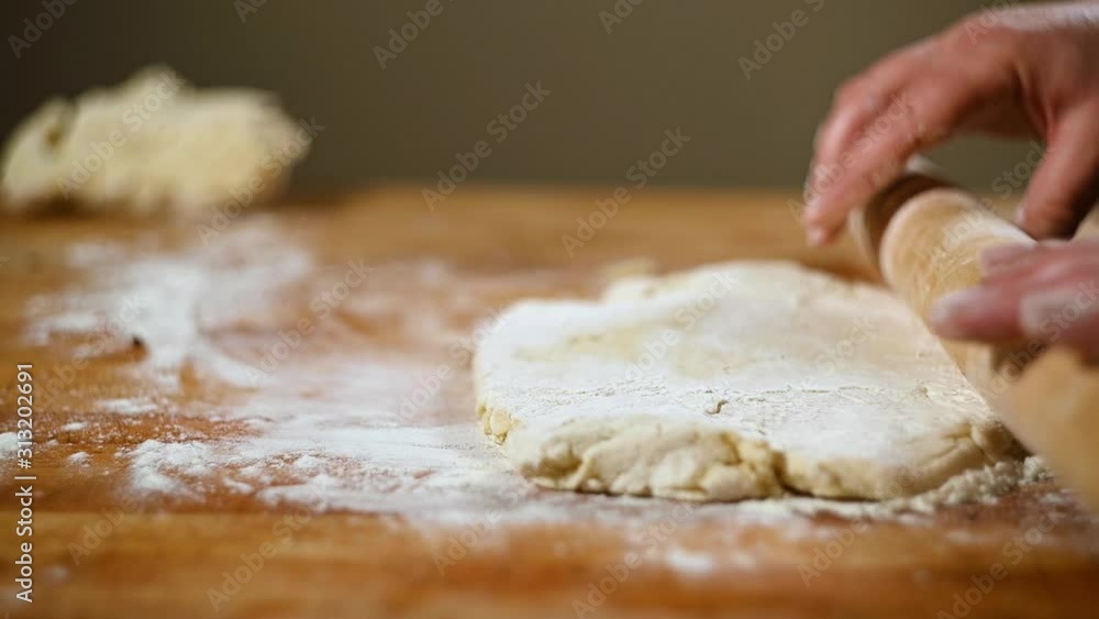 Woman's hands use rolling pin to roll out pie crust on floured board, slow motion. Woman's hands use rolling pin to roll out pie crust on floured board, slow motion.