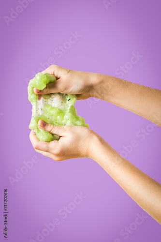 The child's hands stretch lime green on a lilac background.
