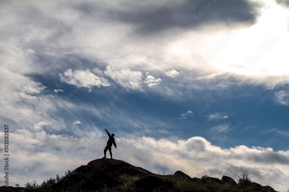 man on top of mountain with blue sky in background