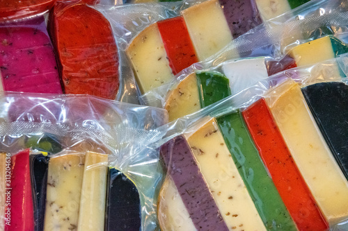 Obraz na plátně Brightly coloured favored cheese wrapped for sale at a market.