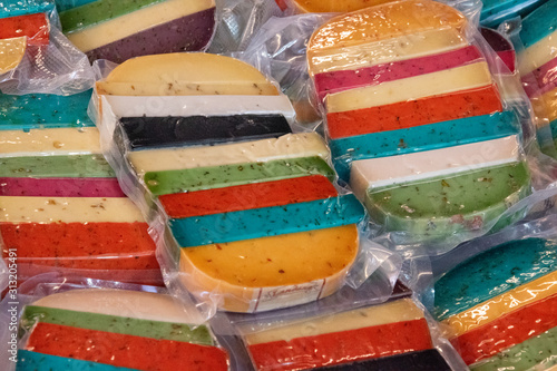 Obraz na plátně Brightly coloured favored cheese wrapped for sale at a market.