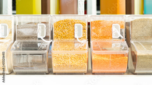 Beautiful and colorful shelf of black and white quinoa, yellow and red lentils and millet grass seeds in containers in refill station. High protein Legumes for plant based diet and vegan. photo