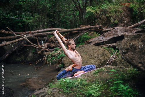 Yoga practice and meditation in nature. Man practicing near river