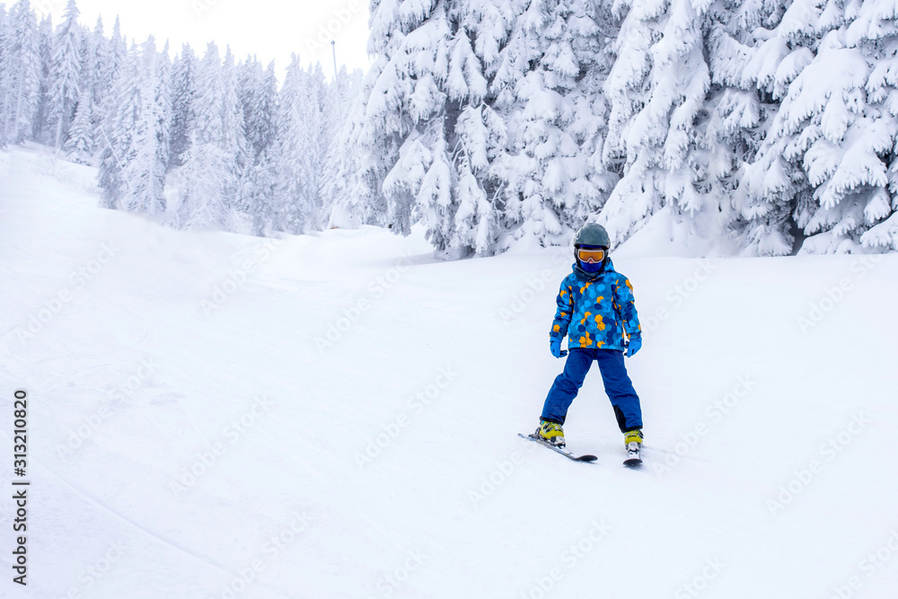 Child skiing in mountain resort during winter vacation