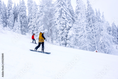 Freeride snowboarders running down the ski slope in mountain resort