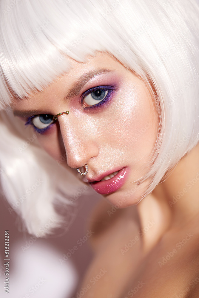Young girl in the image of a fantasy with a piercing. Beautiful model in a white wig with bob and bright makeup. Beauty face. Shining skin. The portrait was taken in the studio. Young girl in the image of a fantasy with a piercing. Beautiful model in a white wig with bob and bright makeup. Beauty face. Shining skin. The portrait was taken in the studio.