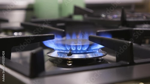 Close view of single gas burner on a stove cooktop, set to high flame.