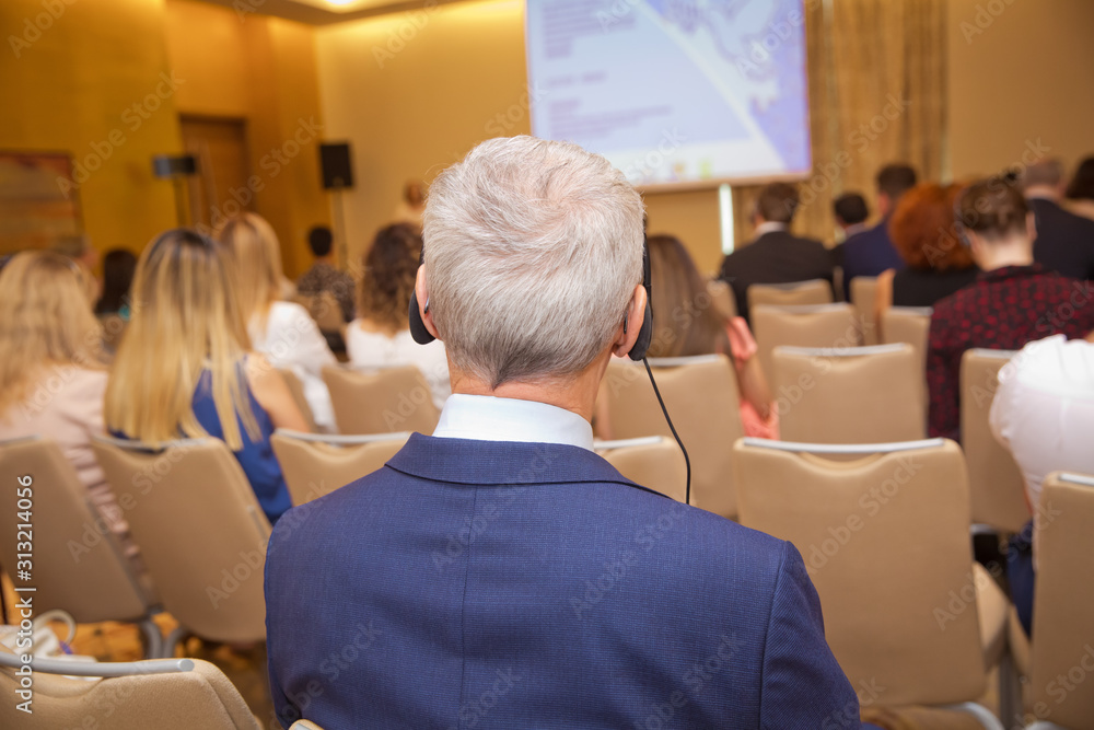 Unrecognizable man using headphones for translation during video conference . bald security guard with the headset to control people . heated debate at a conference discussion . Unrecognizable man using headphones for translation during video conference . bald security guard with the headset to control people . heated debate at a conference discussion .