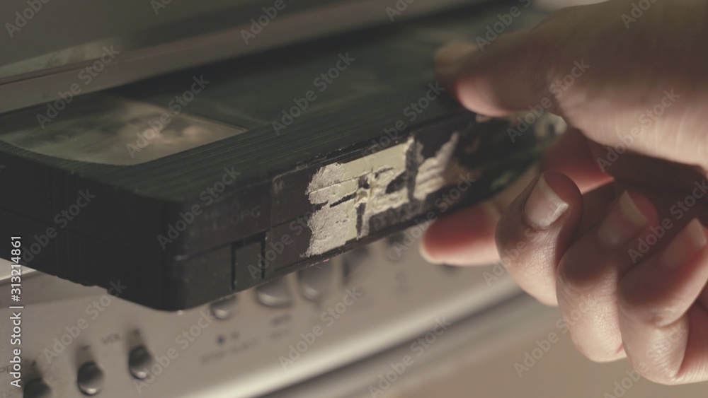 hand put Old VHS Video Cassettes iside the Old Video Recorder. Closeup. videotape cassette
