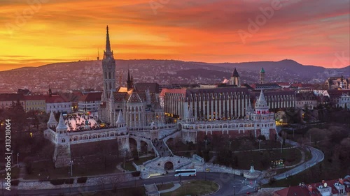Budapest, Hungary - 4K moving time-lapse (hyperlapse) footage of drone flying by Fisherman's Bastion (Halaszbastya) and Matthias Church at dusk when lights turned on with a beautiful golden sunset sky