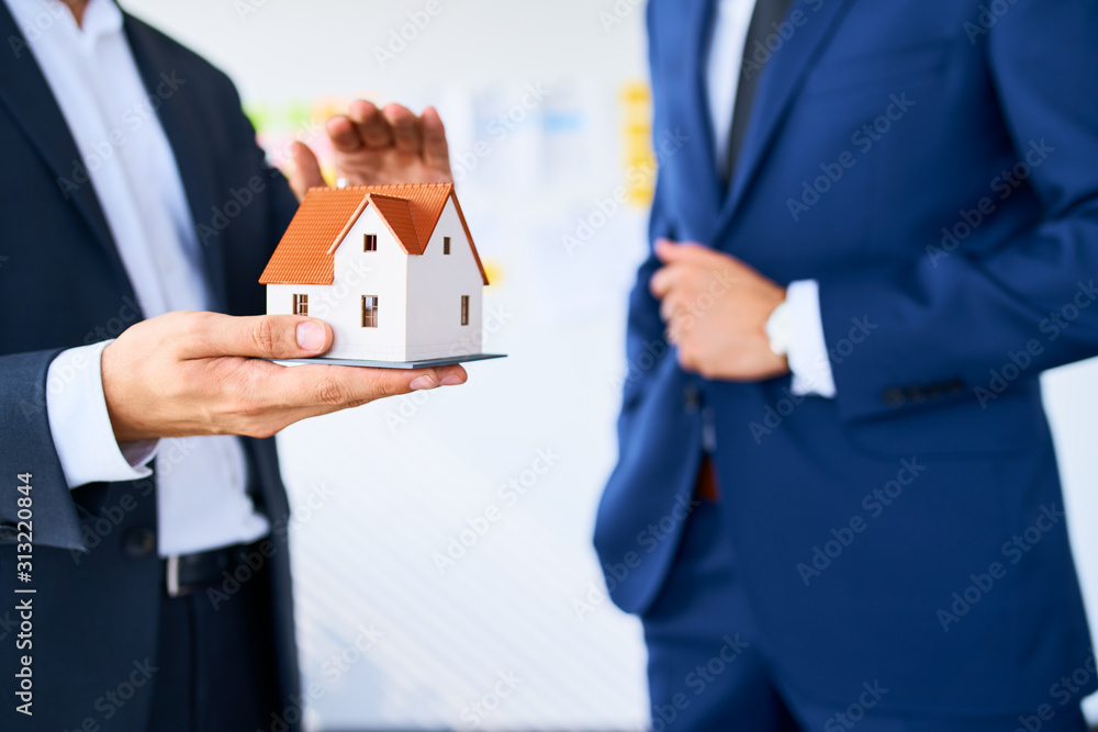 Closeup of real estate agent explaining new home project showing miniature Closeup of real estate agent explaining new home project showing miniature