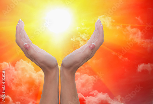 Female hands around the sun in a cloudy sky