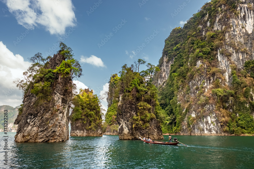 Longtail boat passing by beautiful limestone cliffs in Khao Sok National Park