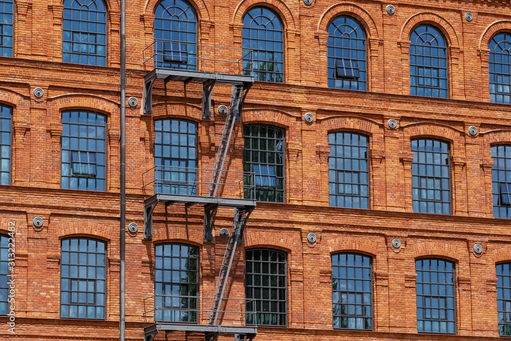 Red brick classic industrial building facade with multiple windows background. 