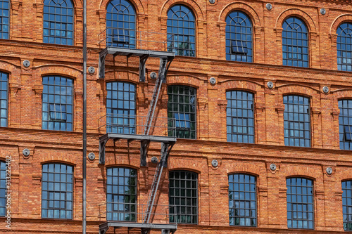 Red brick classic industrial building facade with multiple windows background. 