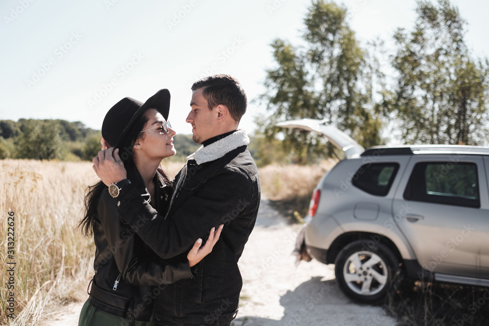 Happy Traveling Couple Dressed in Black Stylish Clothes Enjoying a Car Trip on the Field Road, Vacation Concept Happy Traveling Couple Dressed in Black Stylish Clothes Enjoying a Car Trip on the Field Road, Vacation Concept
