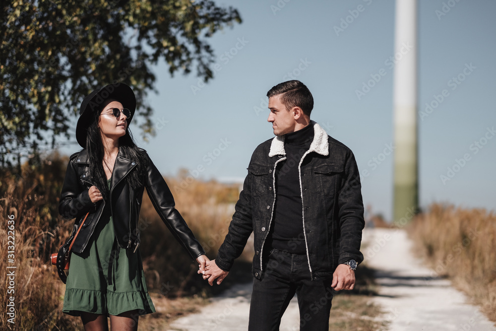 Portrait of Happy Couple Dressed in Black Stylish Clothes Enjoying a Good Time Walking on the Field Portrait of Happy Couple Dressed in Black Stylish Clothes Enjoying a Good Time Walking on the Field