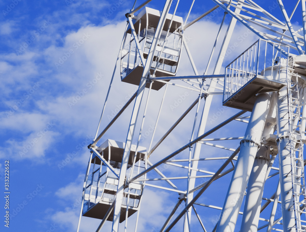 White ferris wheel against the blue sky. Ferris wheel in the park