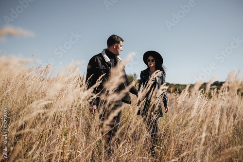 Portrait of Happy Couple Dressed in Black Stylish Clothes Enjoying a Good Time Walking on the Field