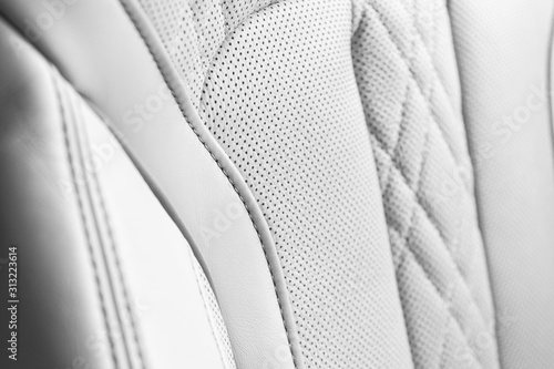 Modern luxury Car white leather interior. Part of perforated leather car seat details. White Perforated leather texture background. Texture, artificial leather with stitching. Perforated leather seats