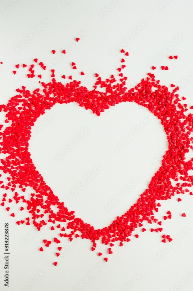 Valentines day love background. Red sugar hearts in the shape of a big heart. Creeting card for Valentines Day. Copy space, top view. Vertical orientation.