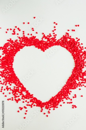 Fototapeta Naklejka Na Ścianę i Meble -  Valentines day love background. Red sugar hearts in the shape of a big heart. Creeting card for Valentines Day. Copy space, top view. Vertical orientation.