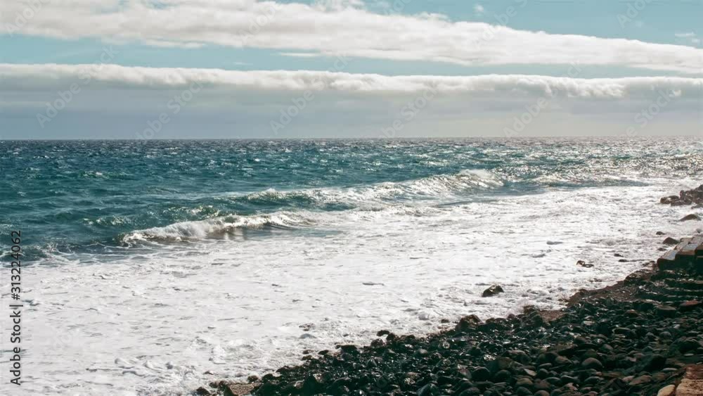 Sea surf. Ocean coast, waves on turquoise water and white foam. Drops fly into camera, volcanic black shore of stones and sand. Sea surf. Ocean coast, waves on turquoise water and white foam. Drops fly into camera, volcanic black shore of stones and sand.