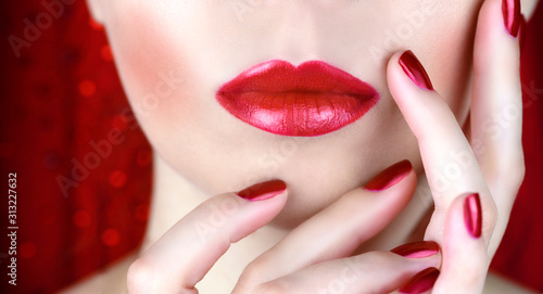 Red lips and red manicure on a red background. Holiday makeup and manicure.