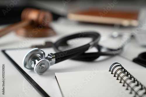 Medical law concept. Gavel, notebook and stethoscope on the white table. Place for text.