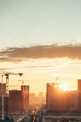 Panorama of construction at sunset. Construction of a residential complex with cranes.