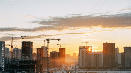  Panorama of construction at sunset. Construction of a residential complex with cranes.