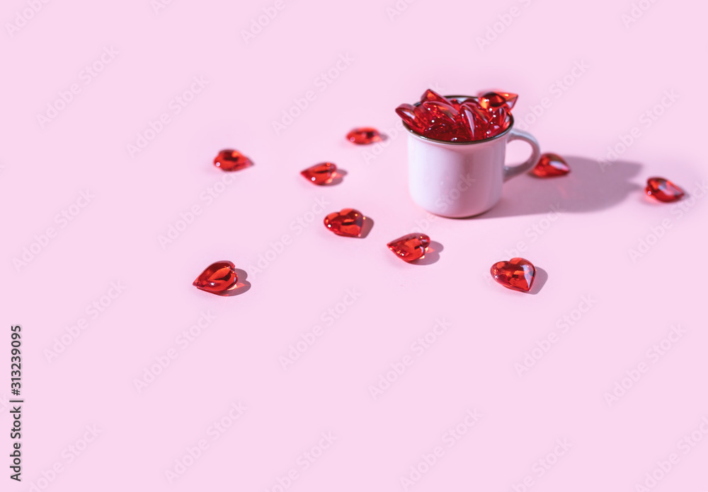 Pink cup full of red glass hearts, hard light, minimalistic concept, stylish background for valentine day.