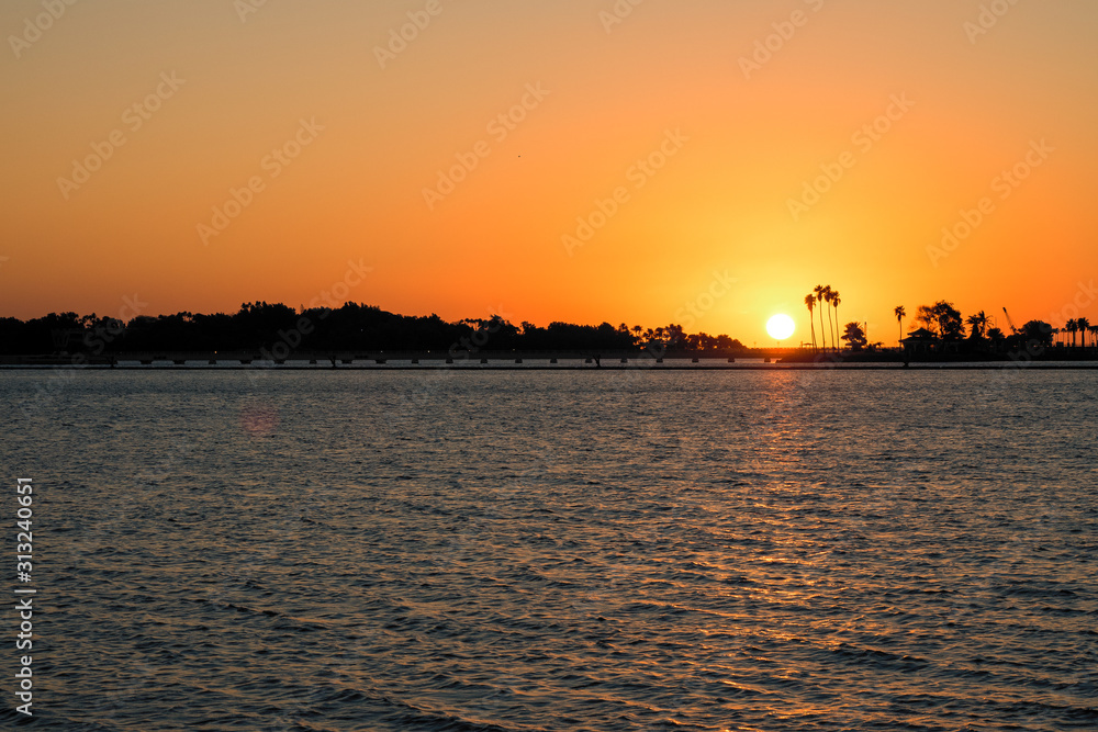 Scenic sunset with silhouettes of palm trees along the shore, seen from the South Corniche in Jeddah, Saudi Arabia