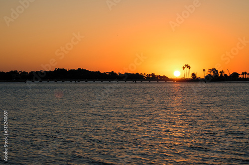Scenic sunset with silhouettes of palm trees along the shore, seen from the South Corniche in Jeddah, Saudi Arabia