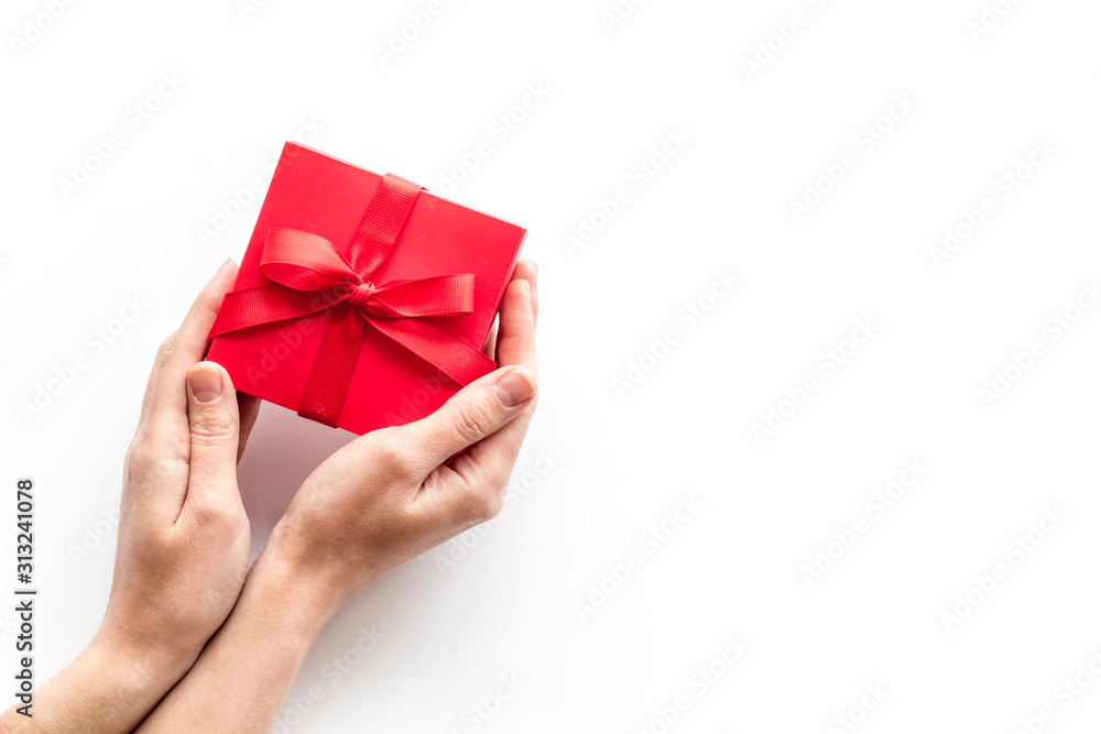 Give a gift on Valentine's Day. Women hand hold beautiful red present box on white background top-down copy space Give a gift on Valentine's Day. Women hand hold beautiful red present box on white background top-down copy space
