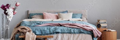 Photography Flowers in glass vase next to king size bed with pastel pink, blue and beige bed