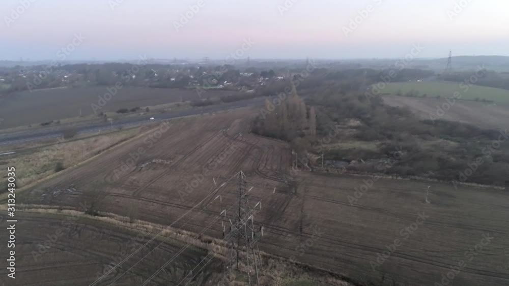 Aerial view flying looking down to pylon tower above UK countryside & motorway. Aerial view flying looking down to pylon tower above UK countryside & motorway.