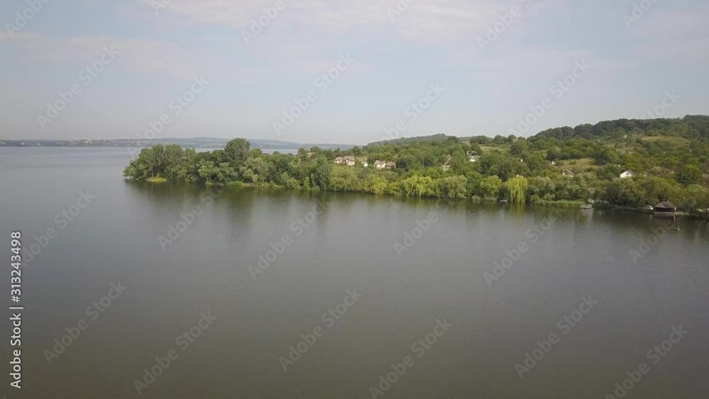 Aerial view of a small village in rural area between green trees on the shore of a big lake. Aerial view of a small village in rural area between green trees on the shore of a big lake.
