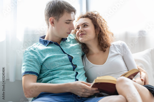 Romantic time.Caucasian couple embrace and reading book in the bed.