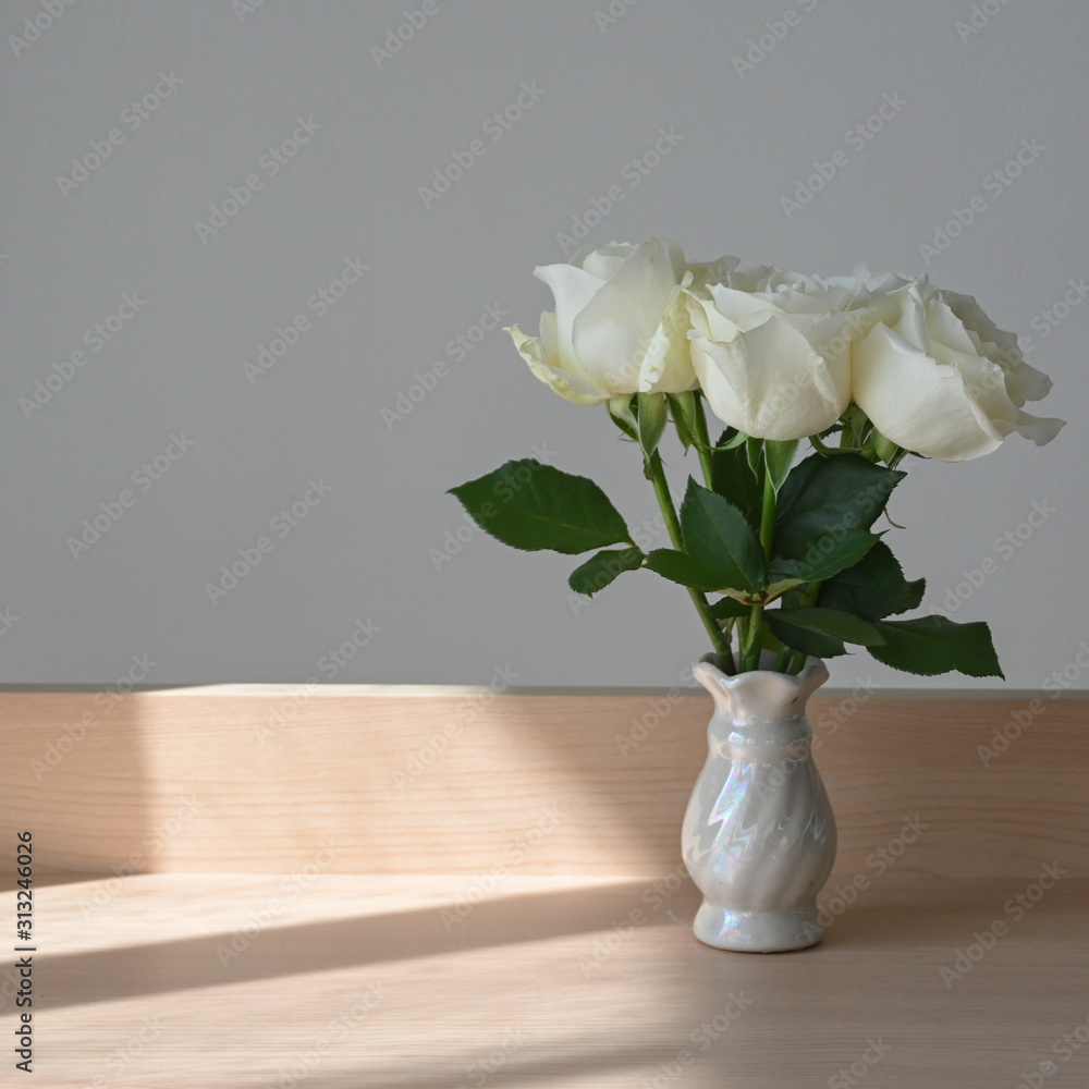 white rose blossom decoration in home, beautiful flower blooming in small vase put on wooden table with sunlight the morning day white rose blossom decoration in home, beautiful flower blooming in small vase put on wooden table with sunlight the morning day