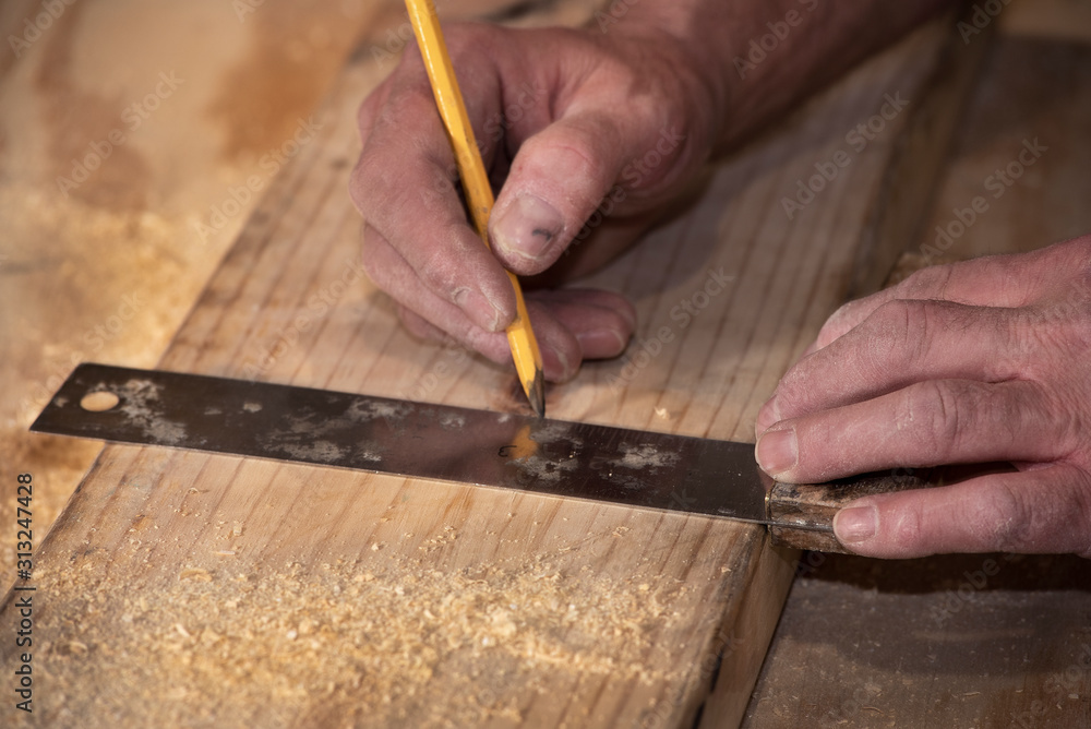 closeup of carpenter marking line on wood board with pencil and wooden square closeup of carpenter marking line on wood board with pencil and wooden square