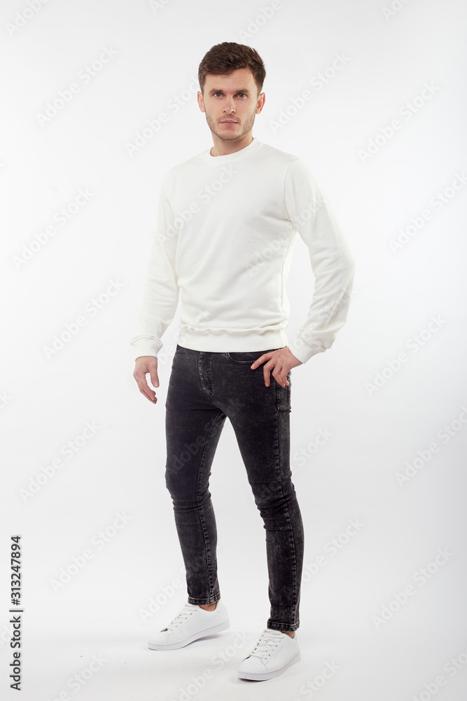 Young european man in white sweater and black pants posing on white background. Isolated. Young european man in white sweater and black pants posing on white background. Isolated.