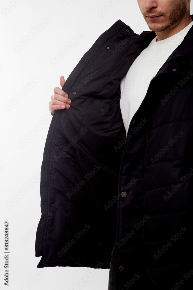 Young european man in white sweater and black pants, black down jacket posing on white background. Isolated. Young european man in white sweater and black pants, black down jacket posing on white background. Isolated.