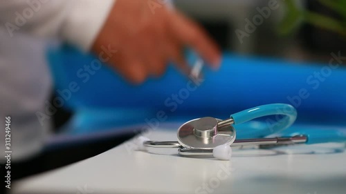 Medicine doctor hand writing prescription clipboard record information of patient in clinic, Female physician working files, have stethoscope on desk in hospital. Healthcare and medical concept. 4K