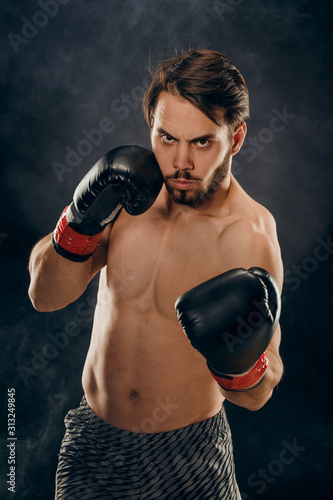 shirtless boxer with gloves on dark background in smoke © fusssergei