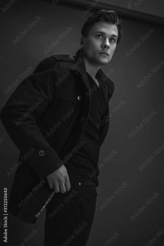 Portrait of stylish man posing on a black background. Wearing a black coat Portrait of stylish man posing on a black background. Wearing a black coat