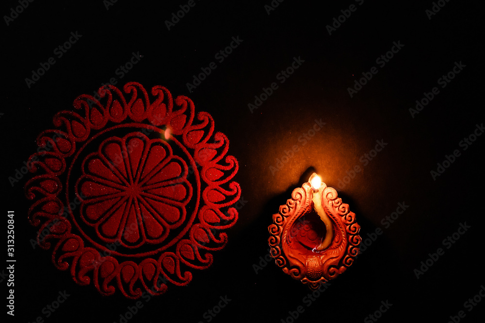 top view mid close-up shot of a terracota lamp and rangoli. festival of lights concept