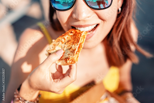 Happy girl eating Mexican fast food quesadilla on the beach. Healthy and tasty snack photo