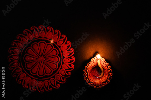 top view mid close-up shot of a terracota lamp and rangoli. festival of lights concept